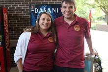 two students posing and smiling with COGS shirts
