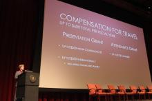 person standing behind a podium onstage during a presentation