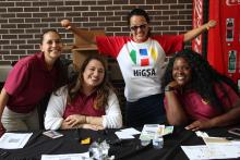 COGS students smiling and posing sitting behind a table