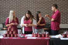 students talking behind a table of COGS merchandise