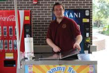 person standing behind booth serving food