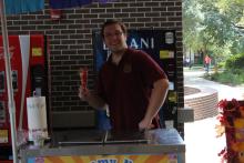 person standing behind booth serving food