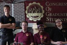 four men posing in front of Congress of Graduate Students Banner