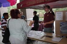 a person behind a booth conversing with someone on the other side of the booth