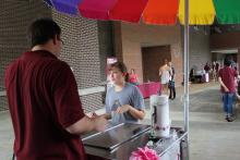 a person behind a booth conversing with someone on the other side of the booth