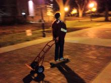 person pulling an empty dolley on a skateboard