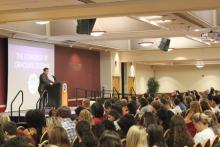 person standing behind a podium and next to a presentation