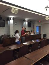 students speaking in the front of a cabinet room