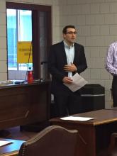 man in a suit speaking in the front of a room