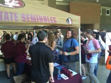 students lining up at a table with an FSU awning