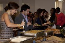 people lining up to select food from a buffet
