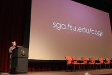 person standing behind a podium onstage during a presentation