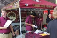 students examining a table during an outdoor event