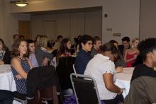 people sitting at tables watching a presentation