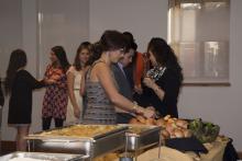 people lining up to select food from a buffet