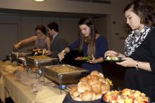 people lining up to select food from a buffet