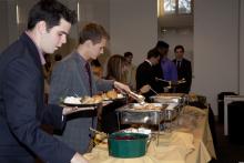 people lining up to select food from a buffet
