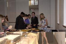 people lining up to select food from a buffet