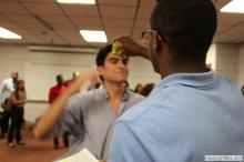 man looking up as a sticky note is placed on his forehead