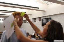 man looking up as a sticky note is placed on his forehead