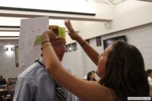 man looking up as a sticky note is placed on his forehead
