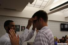 man looking up as a sticky note is placed on his forehead