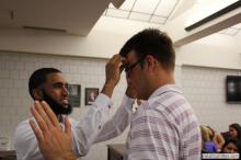 man looking up as a sticky note is placed on his forehead
