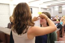 woman looking up as a sticky note is placed on her forehead